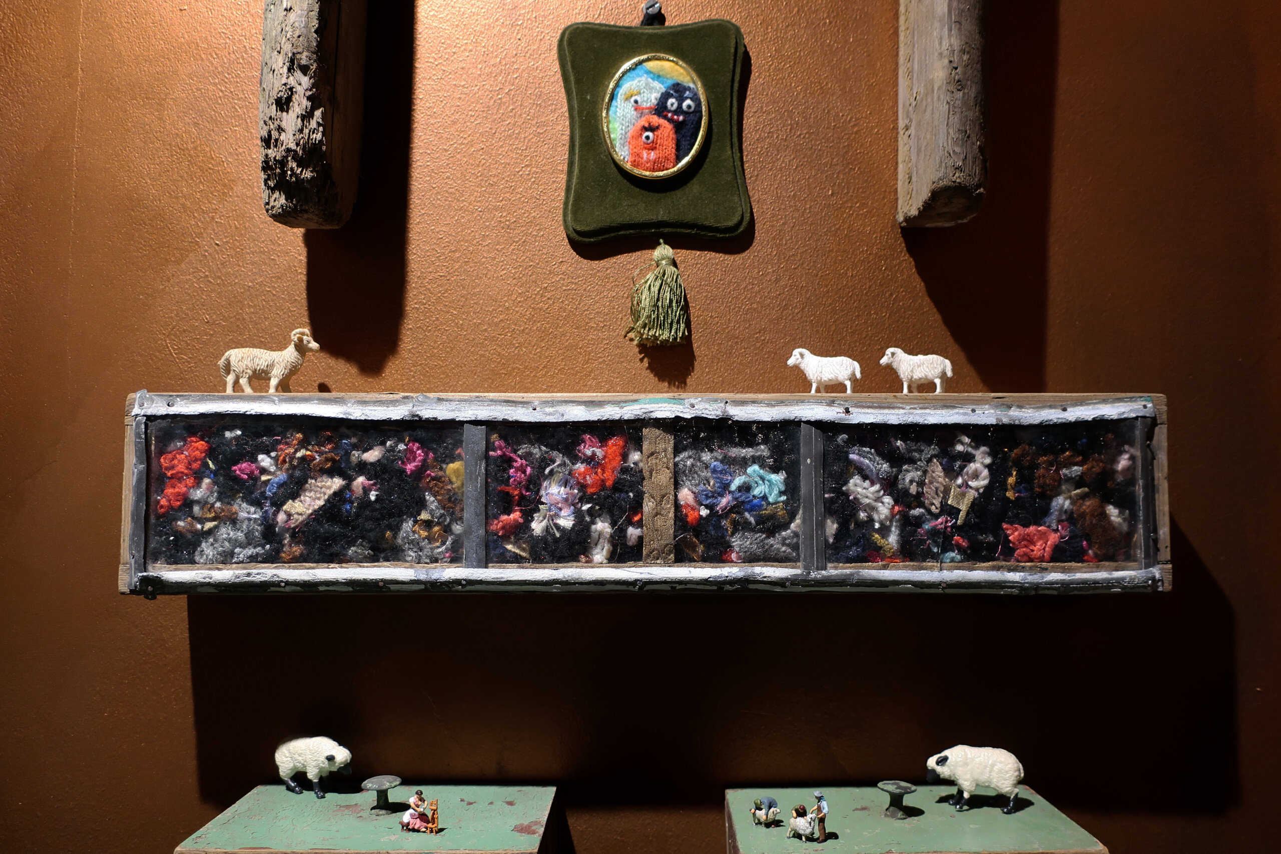 A shelf filled with wool offcuts alongside models of sheep.