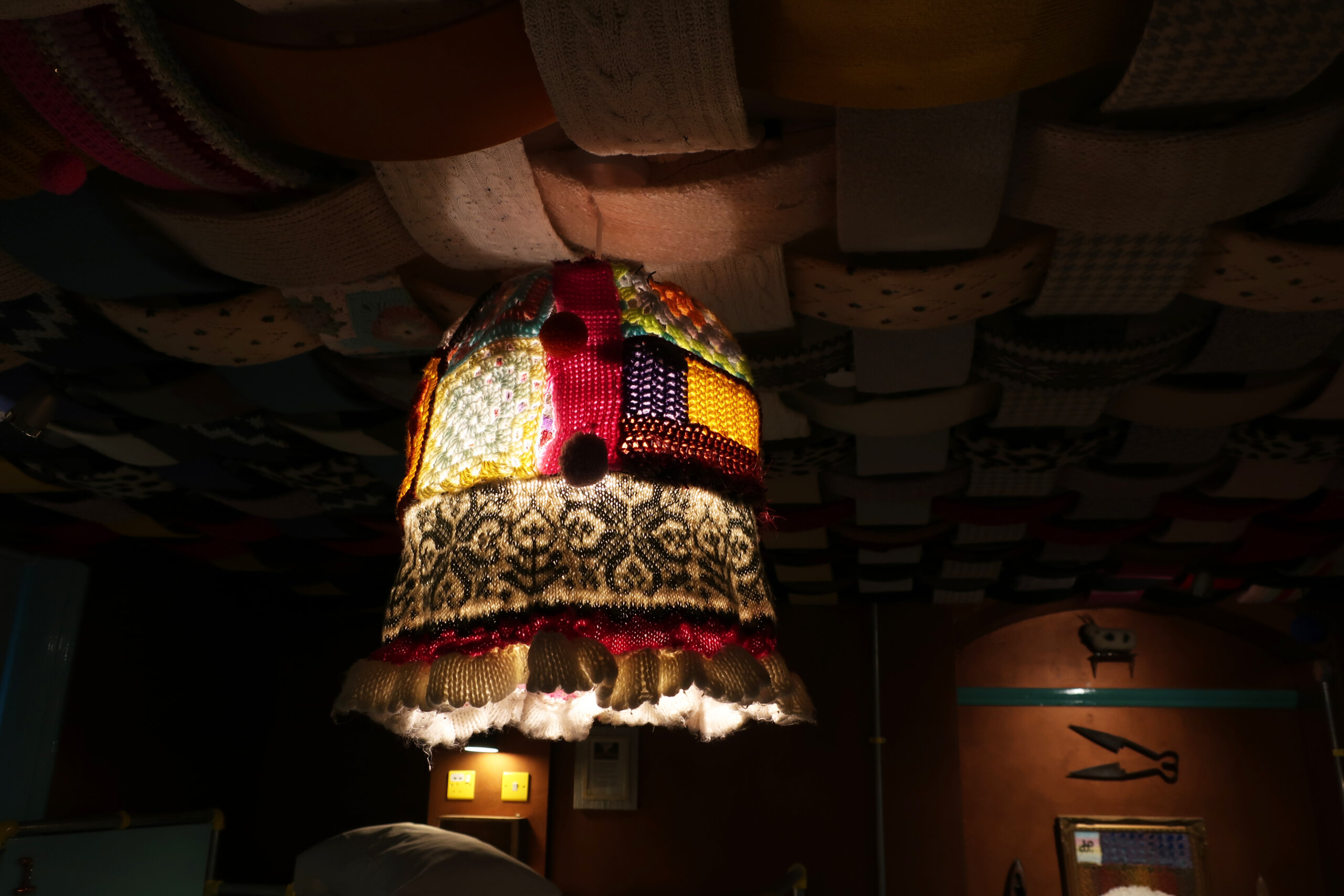 A colourful lampshade made up of patchwork woolen pieces.