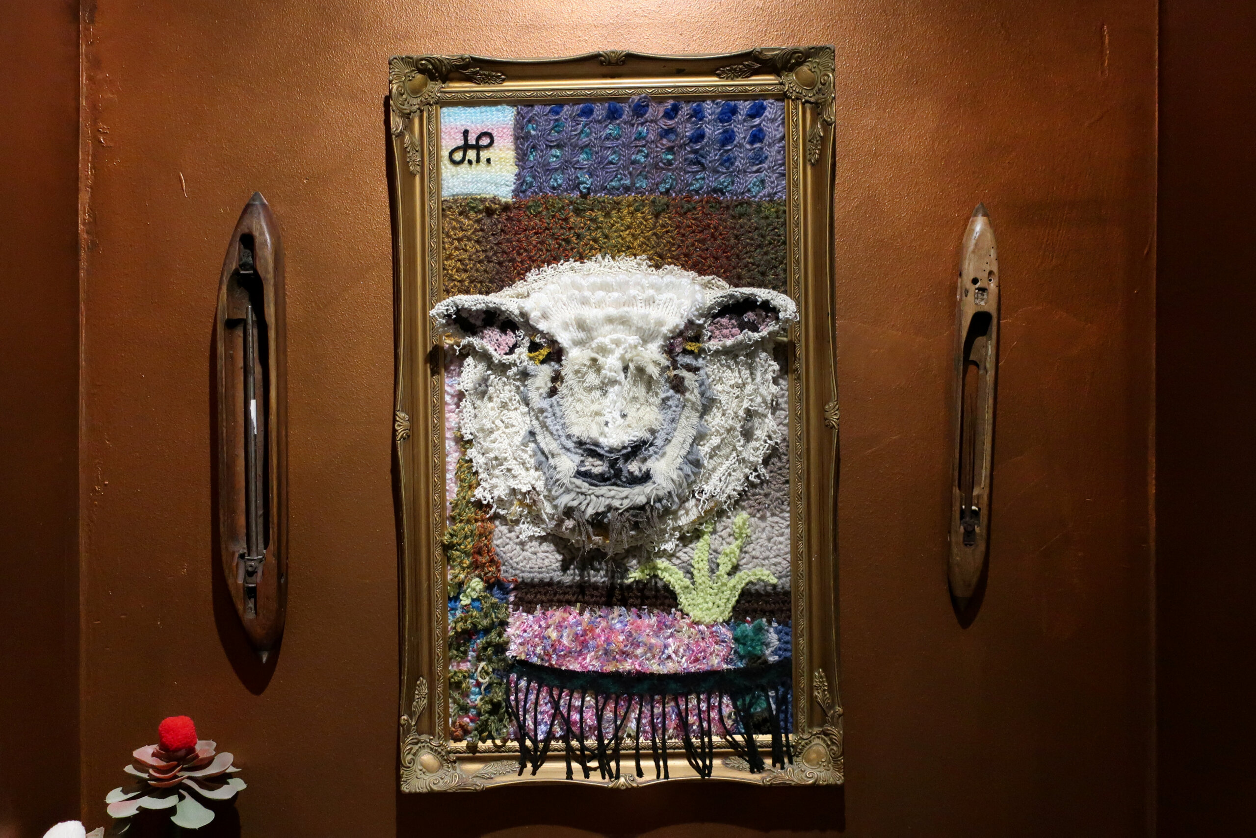 A portrait of a sheep made up of the wool offcuts reused in a picture frame.